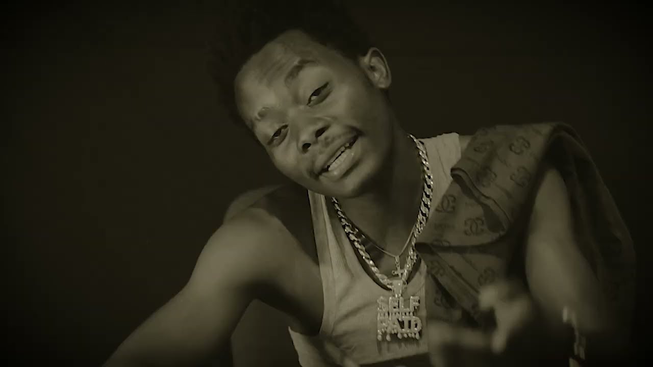 a man with a necklace is rapper from mwansa known as ninebo doug